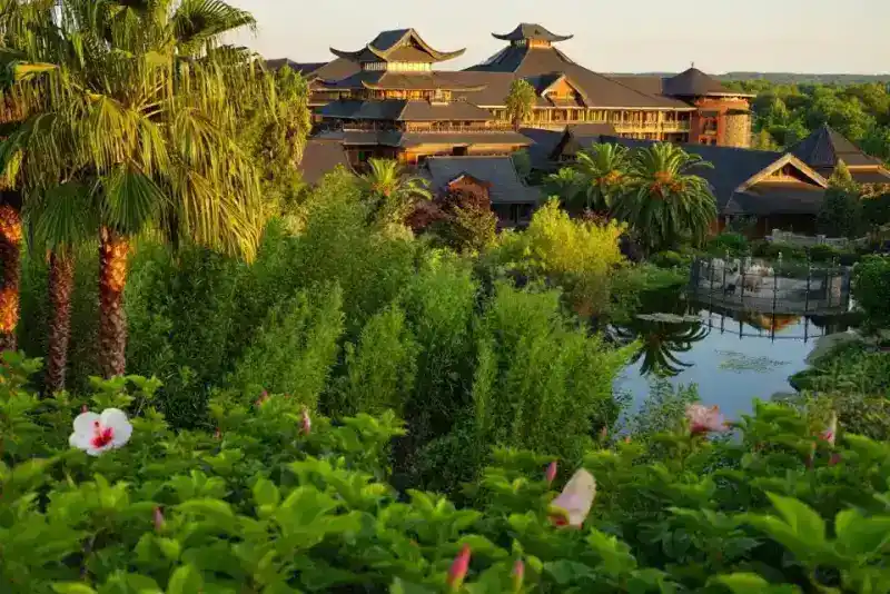Hôtel thématique avec architecture asiatique à toits courbes dans un jardin luxuriant, lumière dorée de fin d'après-midi, reflets d'eau, paysage verdoyant de la vallée du Cher