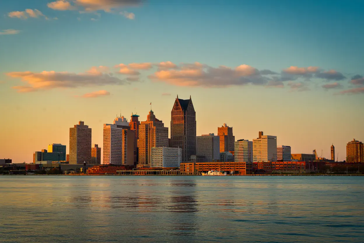 Gratte-ciel Art déco du centre de Detroit au coucher du soleil, vus depuis la rive de la Detroit River, lumière dorée sur les façades, sans personne