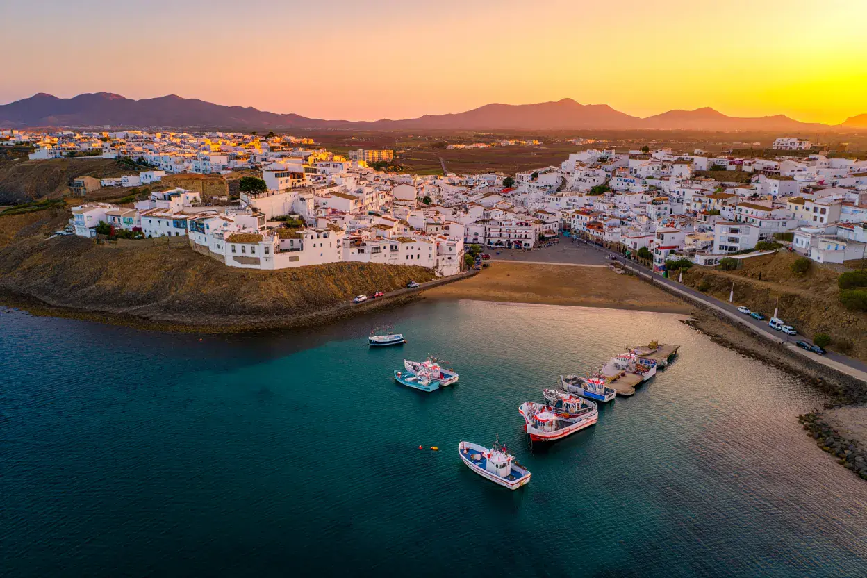 Côte méditerranéenne espagnole au lever du soleil, village blanc aux toits de terre cuite au-dessus d'une mer turquoise, montagnes au loin