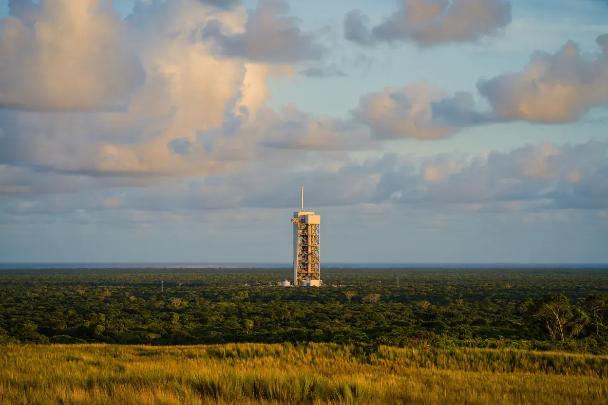 Pas de tir spatial émergeant de la forêt amazonienne de Guyane au lever du soleil, savane tropicale au premier plan, sans personne