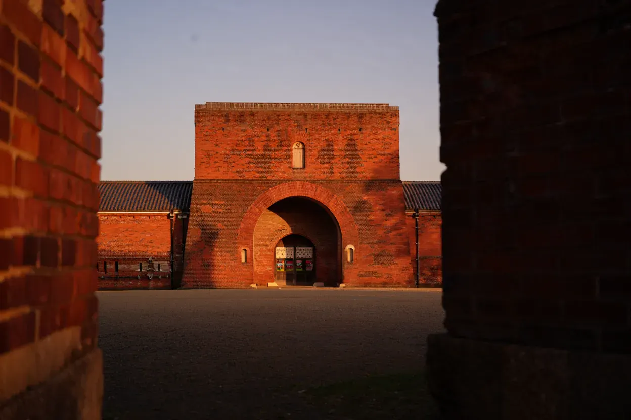 Façade en brique rouge de l'ancienne prison de Nara au Japon, porte monumentale et toits de tuiles japonaises dans la lumière du soir